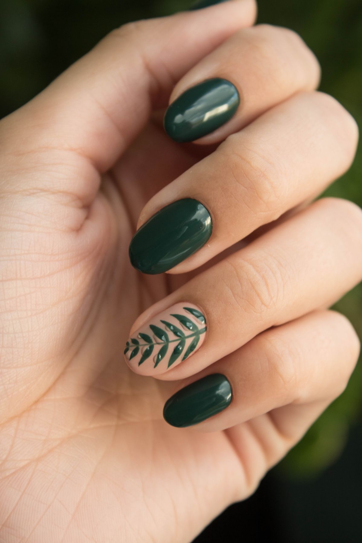 Deep green gel manicure with hand-painted leaf nail art